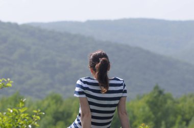 oturan ve dağlara bakan kadın