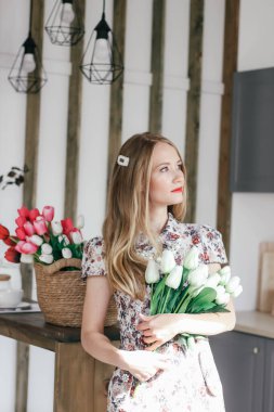 Mutfakta bir sepet lalesi olan sarışın kız.