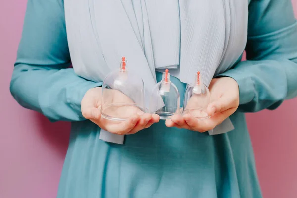 Eşarplı bir kız hijama için kavanozlarını tutuyor. Süpürge pompaları düşüyor