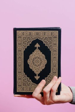 Adamın elinde kutsal Kur 'an var. Pembe bir arka planda.