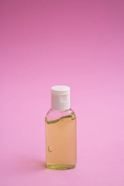Pembe arka planda bir antiseptik şişesi.