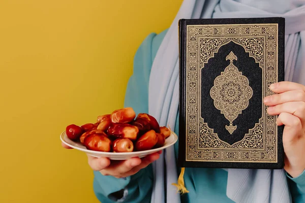 戴头巾的穆斯林女孩拿着日期和古兰经 — 图库照片