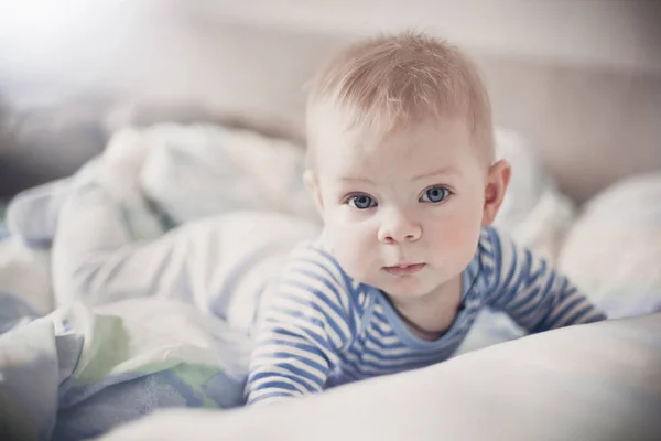 Un Mignon Bebe Blond En Vetements Blancs Et Bleus Se Trouve Dans Un Lit Leger Et