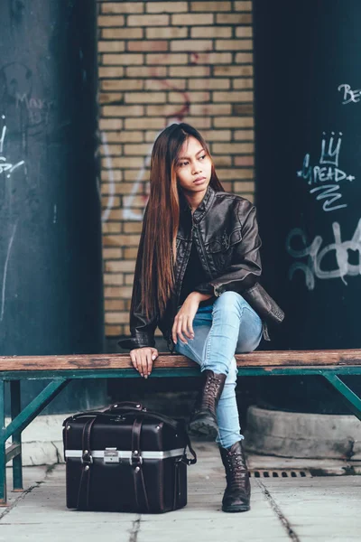 Menina linda em jaqueta de couro posando com saco de couro, estilo hipster — Fotografia de Stock