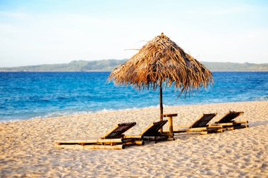 Gün batımı sırasında beyaz kum plaj şezlong ve nipa güneş şemsiyesi