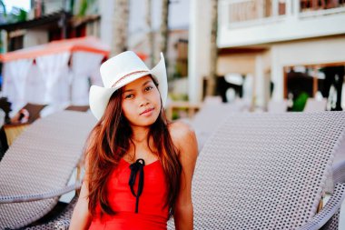 Güzel genç kadın şezlong üzerinde şapka beach resort, yaz tatili oturuyordu.