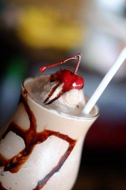 Tatlı çikolata buz sallamak kreması ve vişne üstte kırbaçlanan ile latte