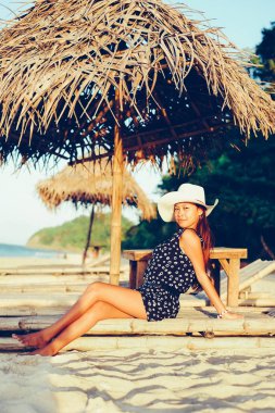 Güzel Asyalı kız beyaz kum plaj adanın günbatımı sırasında şezlong üzerinde rahatlatıcı