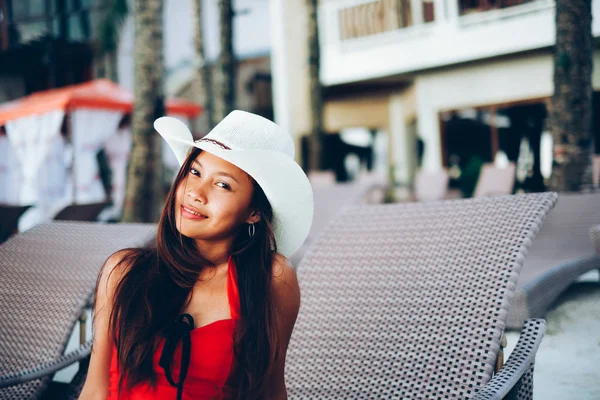 Mulher bonita sentada na cama de sol com o chapéu no resort de praia, férias de verão — Fotografia de Stock