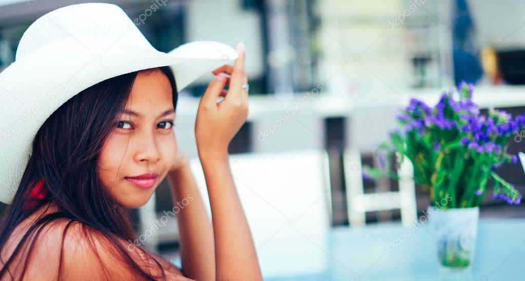 Beautiful young woman smiling with the hat on the beach resort, summer vacation