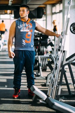 Pazı bir spor salonunda makinede için ağır egzersiz yaparak çekici genç adam