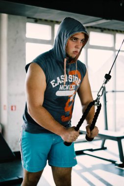 Dayanıklılık egzersiz fitness genç adam spor salonunda açılan ipleri fitness ekipmanları makine ile kaslar.