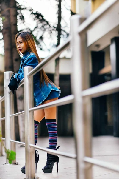 Mujer joven bonita de moda con pantalones vaqueros azules y calcetines largos de rayas en la rodilla — Foto de Stock