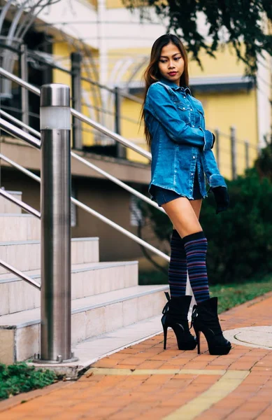 Mujer joven bonita de moda con pantalones vaqueros azules y calcetines largos de rayas en la rodilla — Foto de Stock