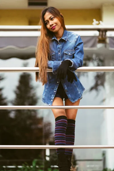 Mujer joven bonita de moda con pantalones vaqueros azules y calcetines largos de rayas en la rodilla — Foto de Stock