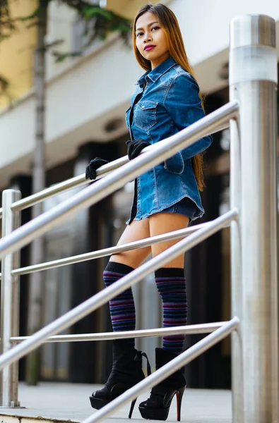 Mujer joven bonita de moda con pantalones vaqueros azules y calcetines largos de rayas en la rodilla —  Fotos de Stock