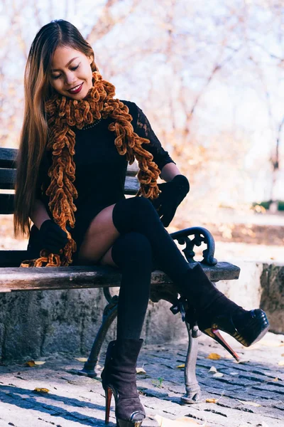ベンチに座っている茶色のスカーフと黒のドレスで美しい少女 — ストック写真