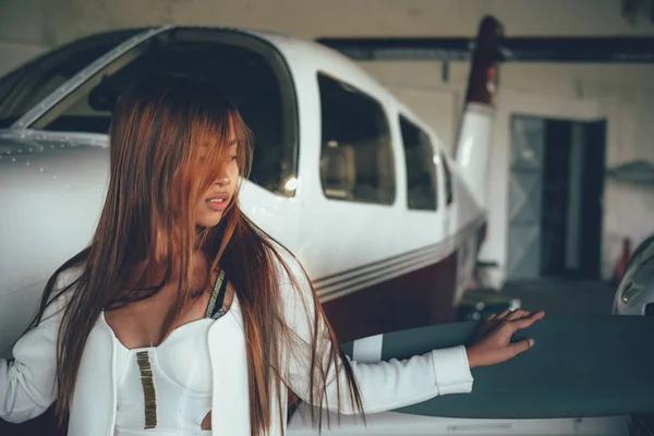 Belo retrato feminino no hangar do avião, com aeronaves modernas — Fotografia de Stock