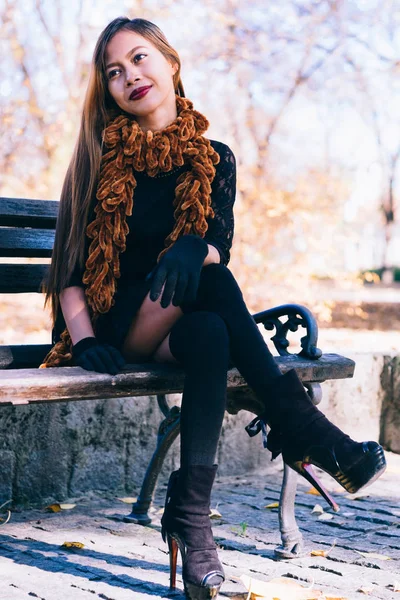 벤치에 앉아 갈색 스카프와 검은 드레스에 아름 다운 소녀 — 스톡 사진
