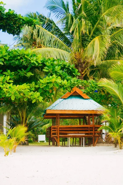 Wooden hut on the white coral sand beach surrounded with lush vegetation — Stock Photo, Image