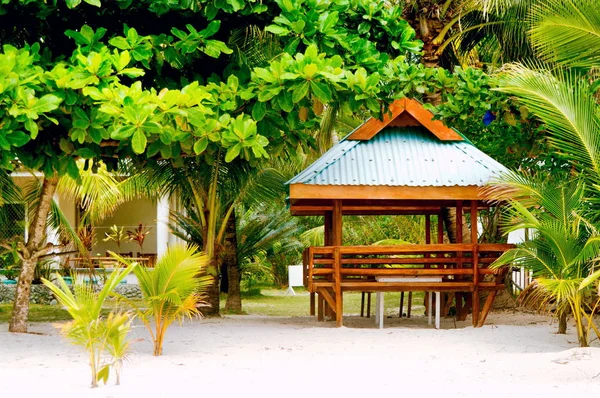 Wooden hut on the white coral sand beach surrounded with lush vegetation — Stock Photo, Image