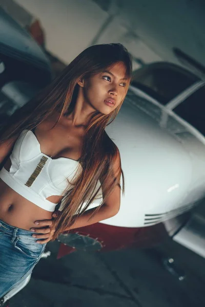 Hermoso retrato femenino en el hangar del avión, con aviones modernos — Foto de Stock