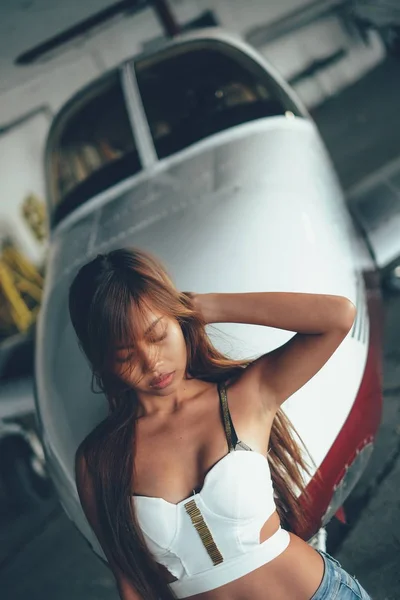 Belo retrato feminino no hangar do avião, com aeronaves modernas — Fotografia de Stock