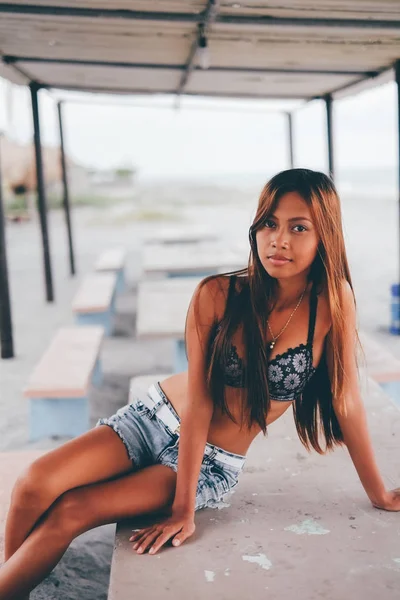 Menina bonita sentada na mesa de concreto sob o guarda-sol — Fotografia de Stock