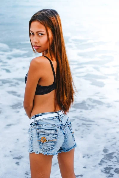 Jovem bela menina asiática de pé na água na praia — Fotografia de Stock
