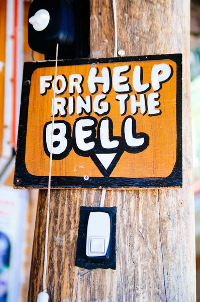 Wooden sign board. ring bell on the main door: For Help ring the bell