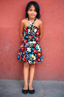 Sevimli küçük kız kırmızı beton duvara ayakta