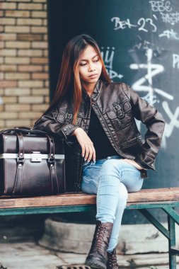 Deri ceket, deri çanta, yenilikçi, Retro Vintage tarzı ile poz bankta oturmuş güzel genç kadın