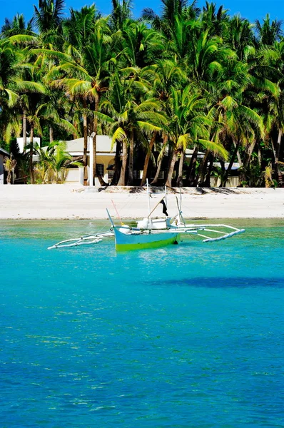 Empty fishing boats docked at the turquoise colored ocean coast near white coral sand beach in the afternoon on the ocean horizon in Asia — Stock Photo, Image