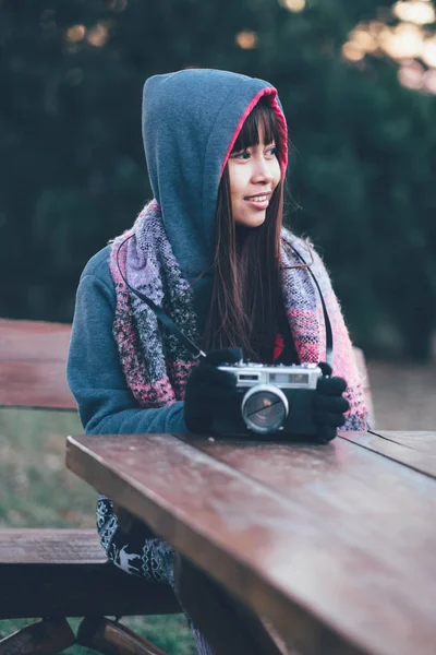 Female photographer holding old retro film camera. Woman in winter coat with scarf during cold weather outside — Stock Photo, Image