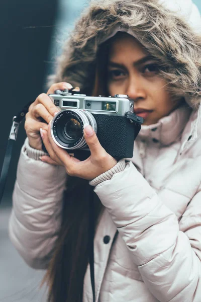 Beautiful girl in a winter coat photographing outside using Vintage Retro film camera. urban environment — Stock Photo, Image