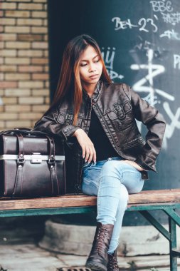 Deri çanta, hippi tarzı ile bankta oturmuş deri ceketli güzel kız