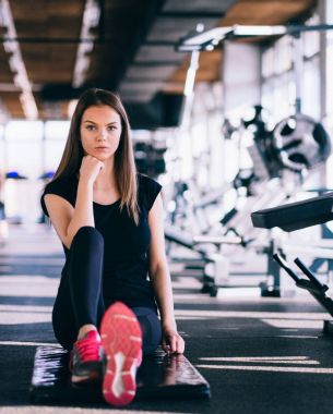 Modern bir fitness Center'da siyah mat germe egzersizleri çekici ince kadın yapıyor. Yorgun kız yoğun egzersiz yaptıktan sonra rahatlatıcı