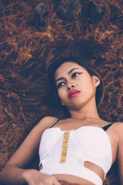 Menina bonita nova que coloca no chão da floresta, com o cabelo emaranhado em pequenos ramos que caíram de pinheiros, conceito de moda — Fotografia de Stock