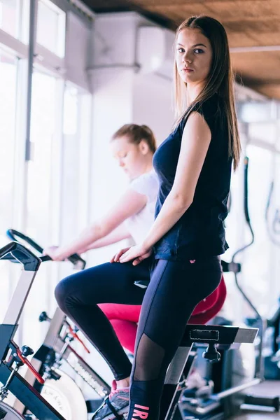 スポーツ ジムでエアロバイクに若い女性 — ストック写真