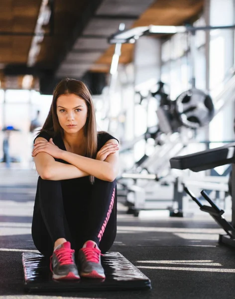 Vonzó karcsú női csinál, nyújtó gyakorlatok, fekete Matt, a modern fitneszközpontban. Fáradt lány pihentető az intenzív edzés után — Stock Fotó