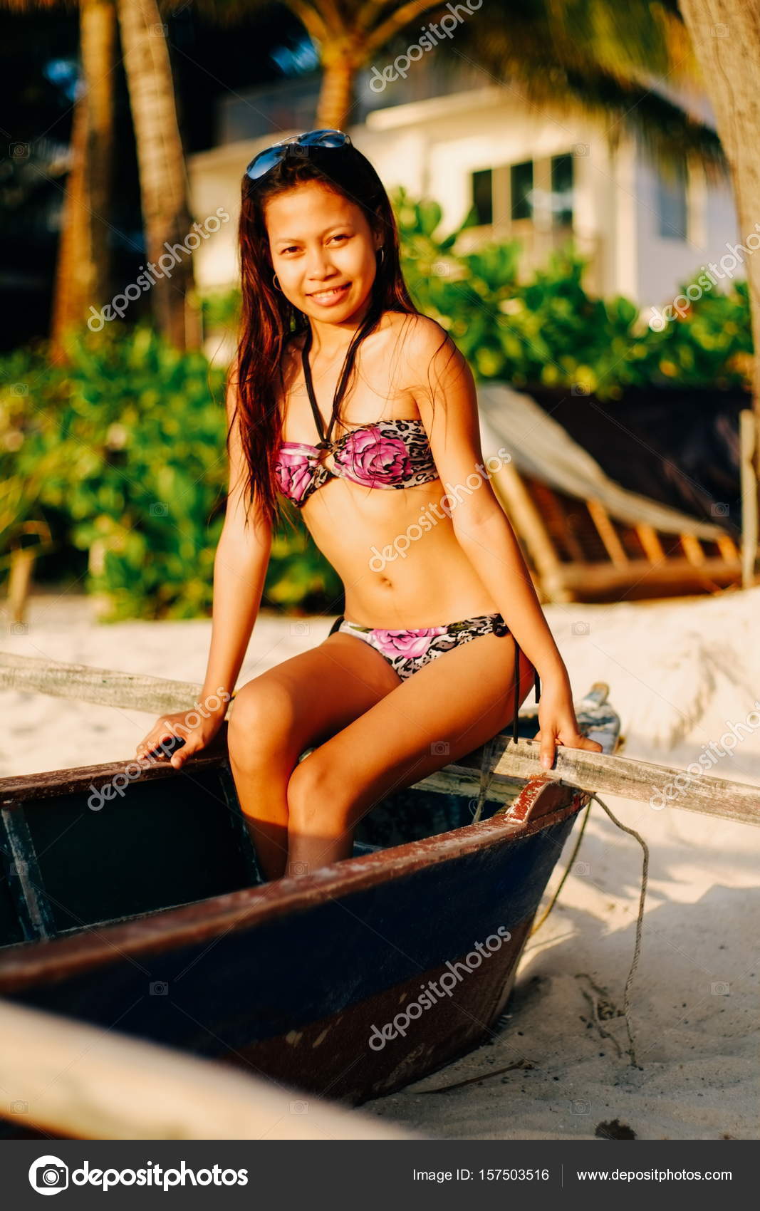 Happy young beautiful girl in a summer swimsuit sitting on an old
