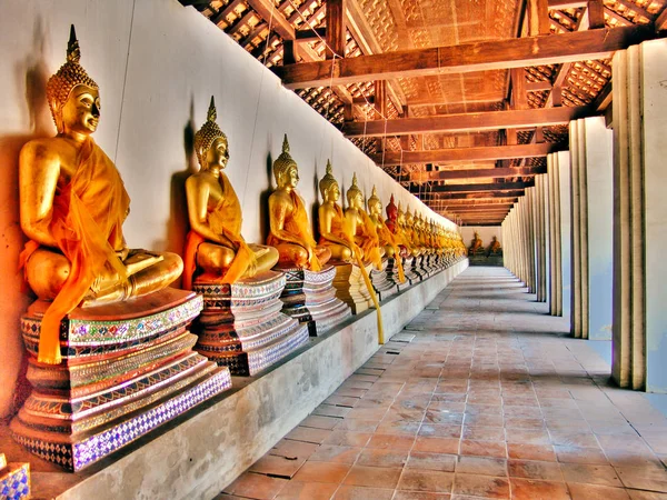 Ряд золотой статуи Будды сидит в храме Ват Пхуттхайсаван в историческом парке Аюттхая — стоковое фото