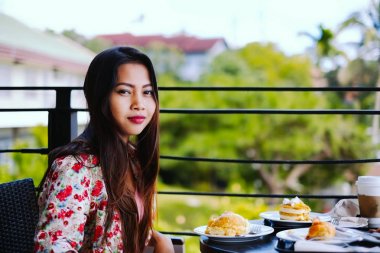 Güzel genç kız açık havada kafede yaz gününde yemek