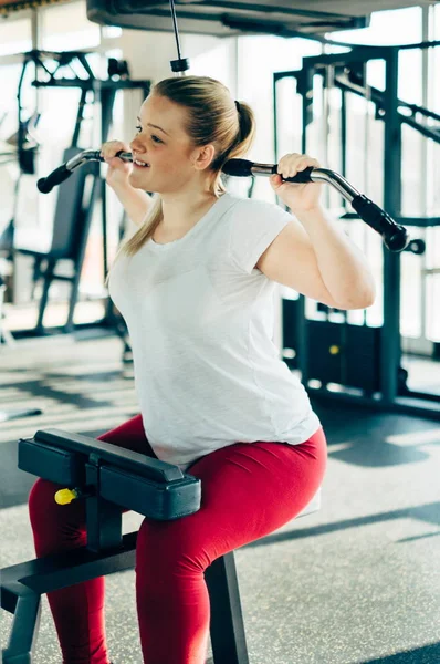 Lat makine ile fitness spor salonunda egzersiz genç acemi kız