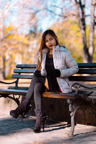 晴れた秋の日に公園でスタイリッシュな暖かい服装でベンチに座って若い美しい女性の肖像画。市では、カジュアルなライフ スタイル — ストック写真