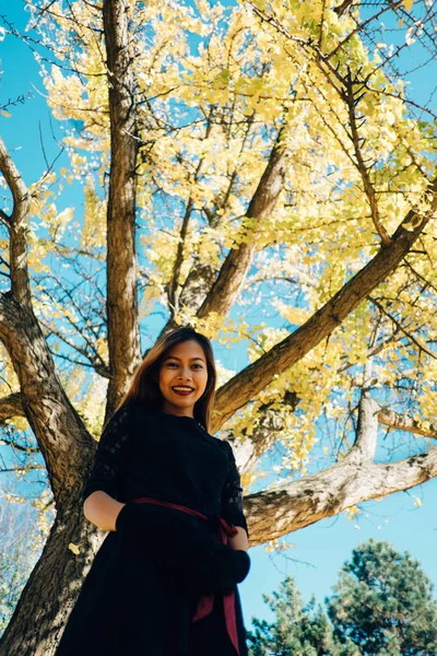  Park güneşli sonbahar gününde mutlu genç kadın gülümsüyor. Siyah retro elbise sonbahar moda stil neşeli güzel kız