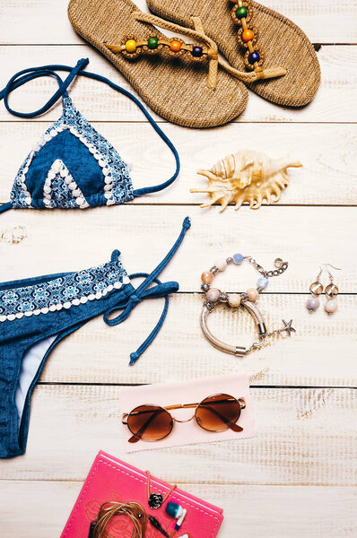 Flat lay of summer fashion camera, sunglasses and other girl accessories on white wooden background