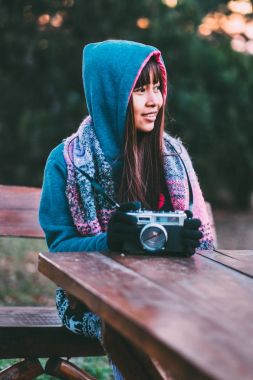 Genç kadın fotoğrafçı kazak ve renkli atkı öğleden sonra boyunca giyiyor soğuk havalarda dışarıda günbatımı
