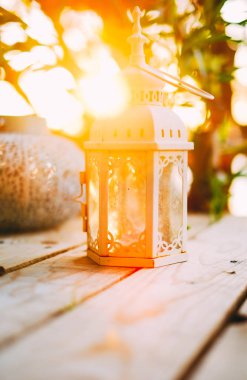 Closeup dekoratif beyaz mum fener içinde belgili tanımlık geçmiş güzel gün batımı ile ahşap tablo