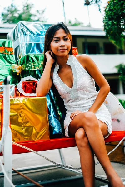 熱帯のクリスマス コンセプト。光沢のあるカラフルな贈り物をサンタ クロースのそりの若い女性 — ストック写真